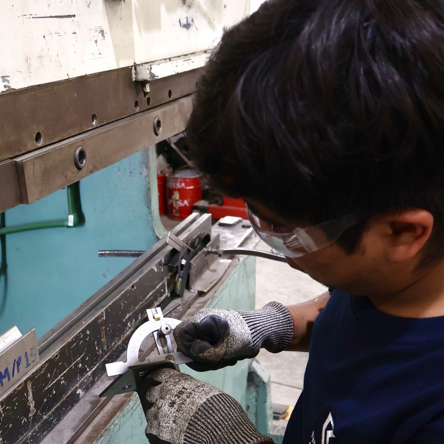 Técnico de Rolacero Multiprocesos ajustando un calibrador de precisión en la dobladora