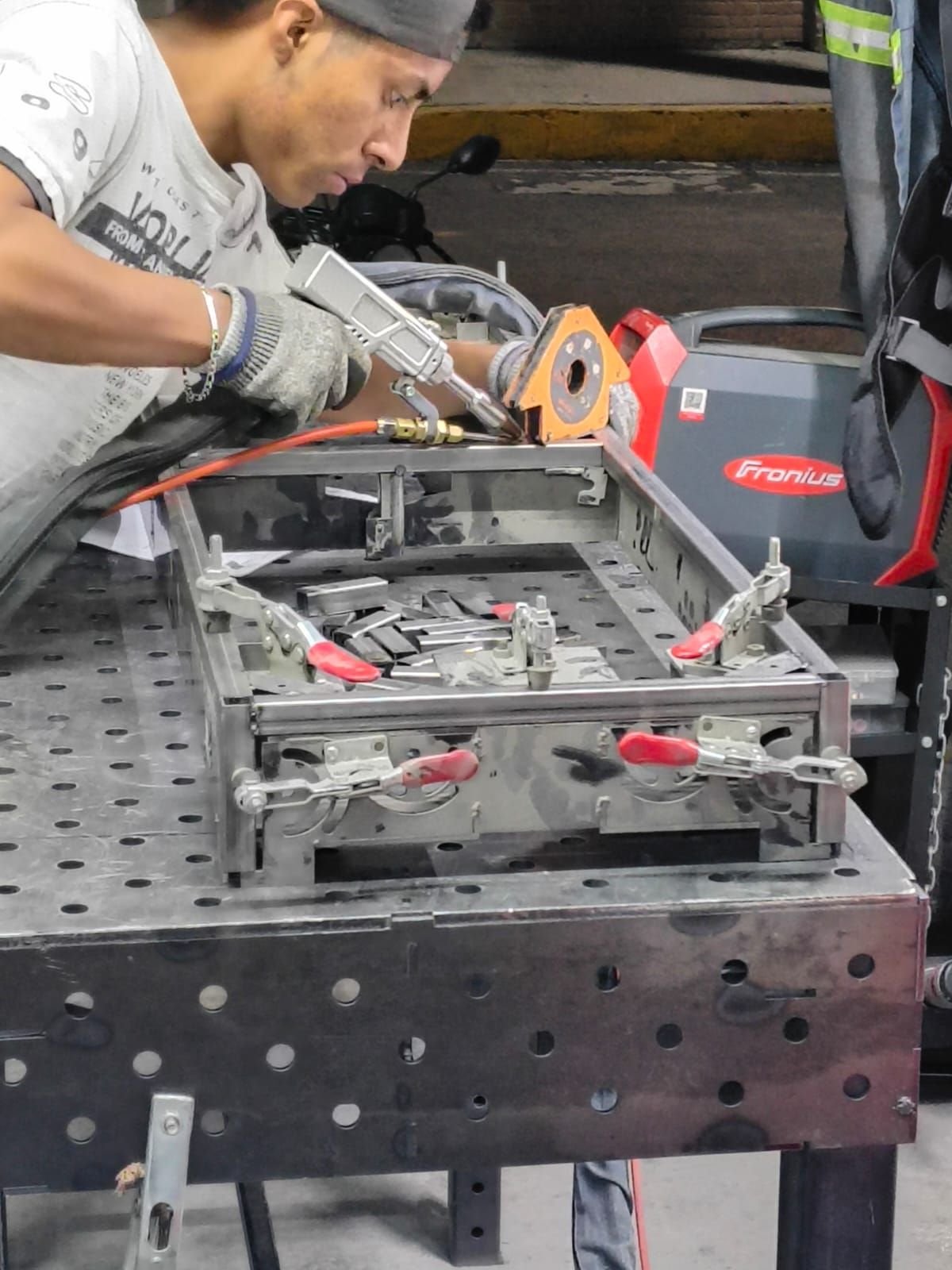 Técnico de Rolacero Multiprocesos con equipo de protección personal ensamblando un jig metálico